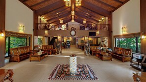 Un hall d’entrée spacieux avec de hauts plafonds, des meubles en bois et une colonne décorative centrale.