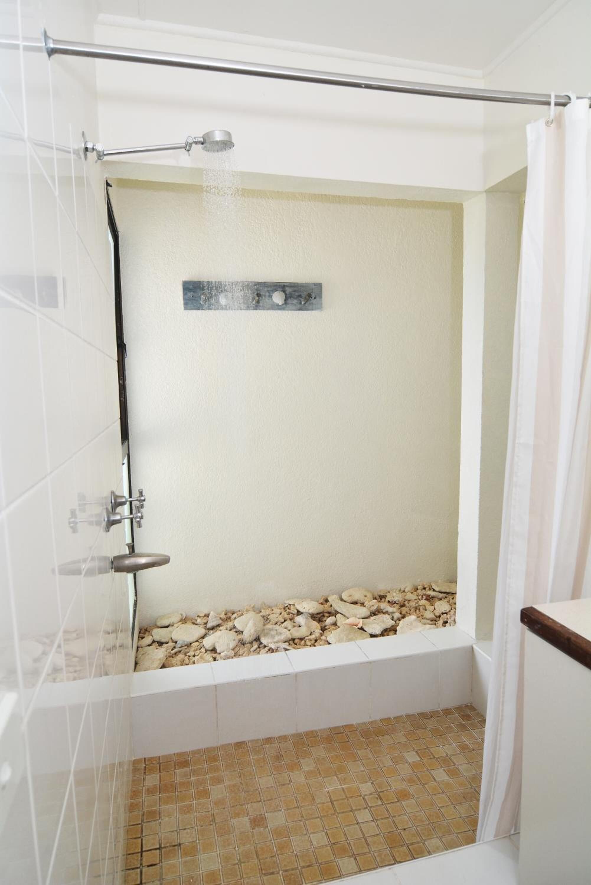 Ducha con puerta de cristal, cabezal de ducha metálico y suelo de baldosas.