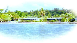 Una propiedad frente a la playa con varias villas, vista despejada al océano y abundante vegetación.
