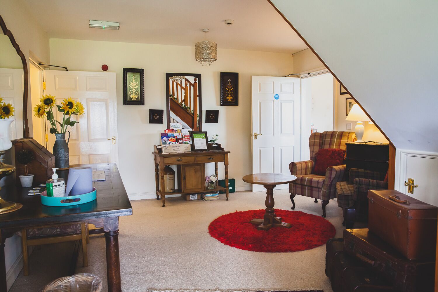 A cozy living room with a wooden table, a red rug, and a plaid armchair.