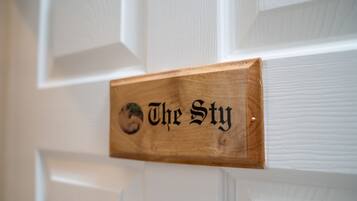 A wooden sign with the text "The Sty" mounted on a white door.