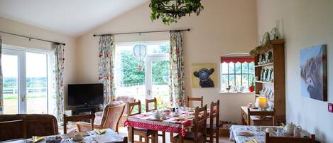 A cozy dining area with a chandelier, a television, and a view of the outdoors.