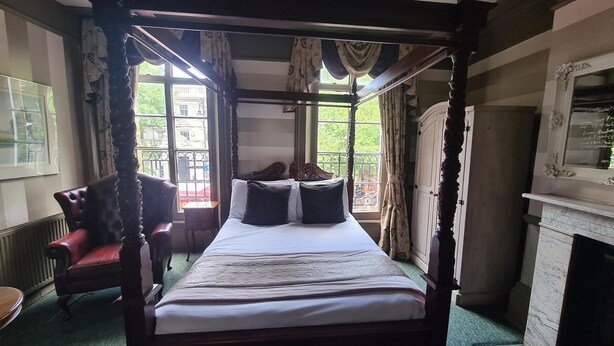 A four-poster canopy bed with a view of the garden through the window. - Kings Boutique Hotel (London)