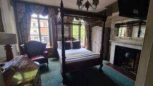 A four-poster bed with a canopy, a fireplace, and a view of the outside through large windows. - Kings Boutique Hotel (London)