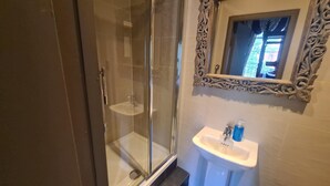 A bathroom with a glass-enclosed shower, a white sink, and a decorative mirror with an ornate frame. - Kings Boutique Hotel (London)