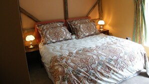 Een slaapkamer met een groot bed, twee nachtkastjes met lampen en een raam met gordijnen.