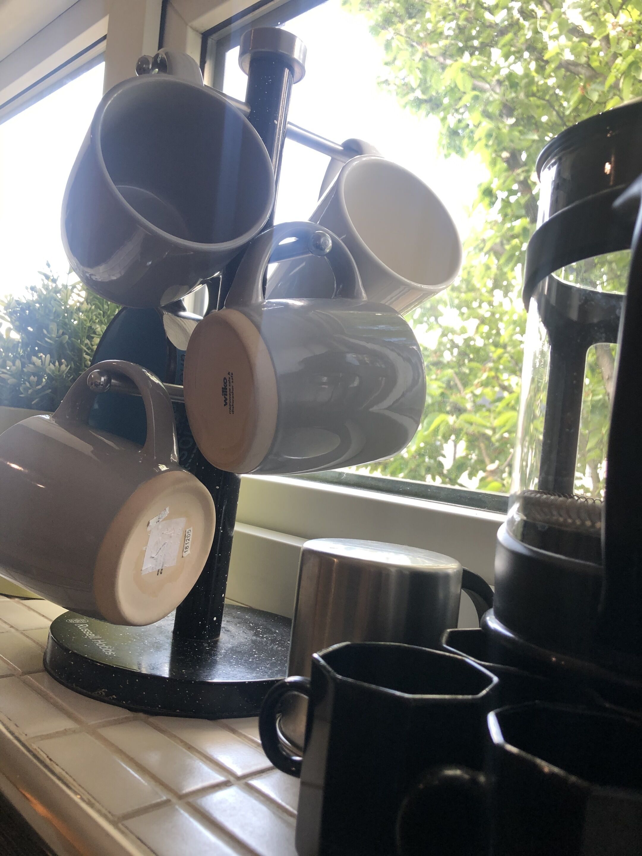 A kitchen counter with various kitchenware, including a coffee maker and several mugs.