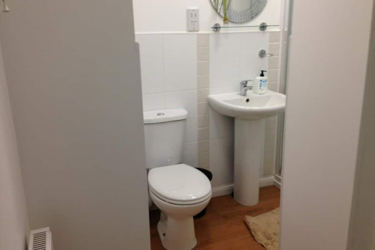 Un baño pequeño y funcional con inodoro blanco, lavamanos sobre pedestal y espejo sobre el lavamanos.
