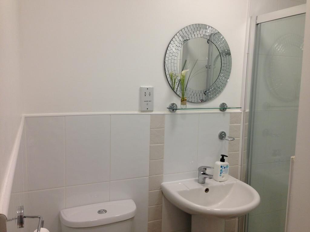 A bathroom with a toilet, sink, and a glass shower enclosure.