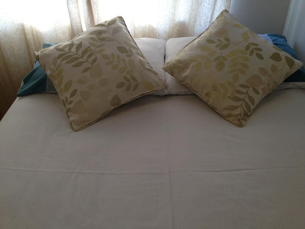A bed with two pillows and a blue blanket.