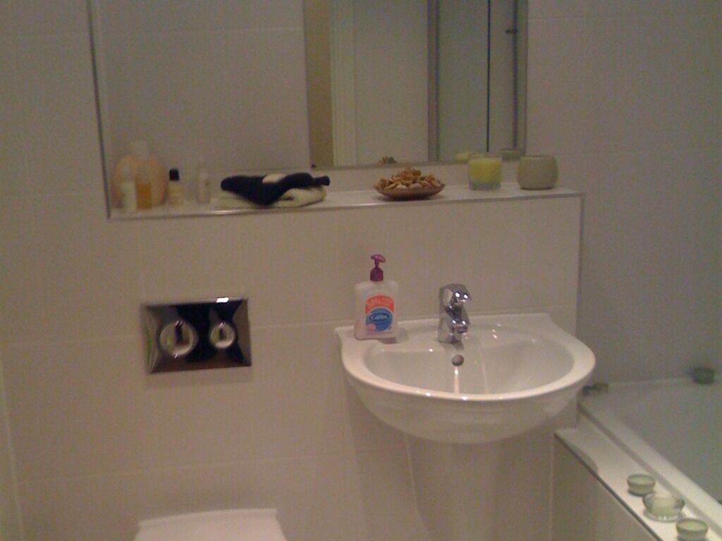 A bathroom with a sink, mirror, and toiletries.