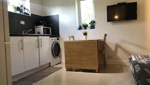 Eine kompakte Küche mit Waschmaschine, Mikrowelle und einem Essbereich mit Tisch und Stühlen.