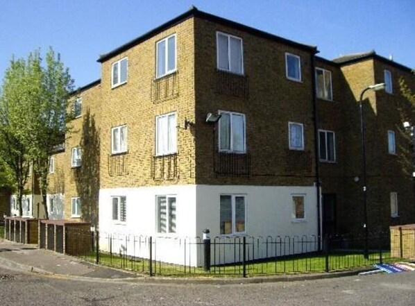 A two-story residential building with a brick facade, white lower section, and multiple windows.