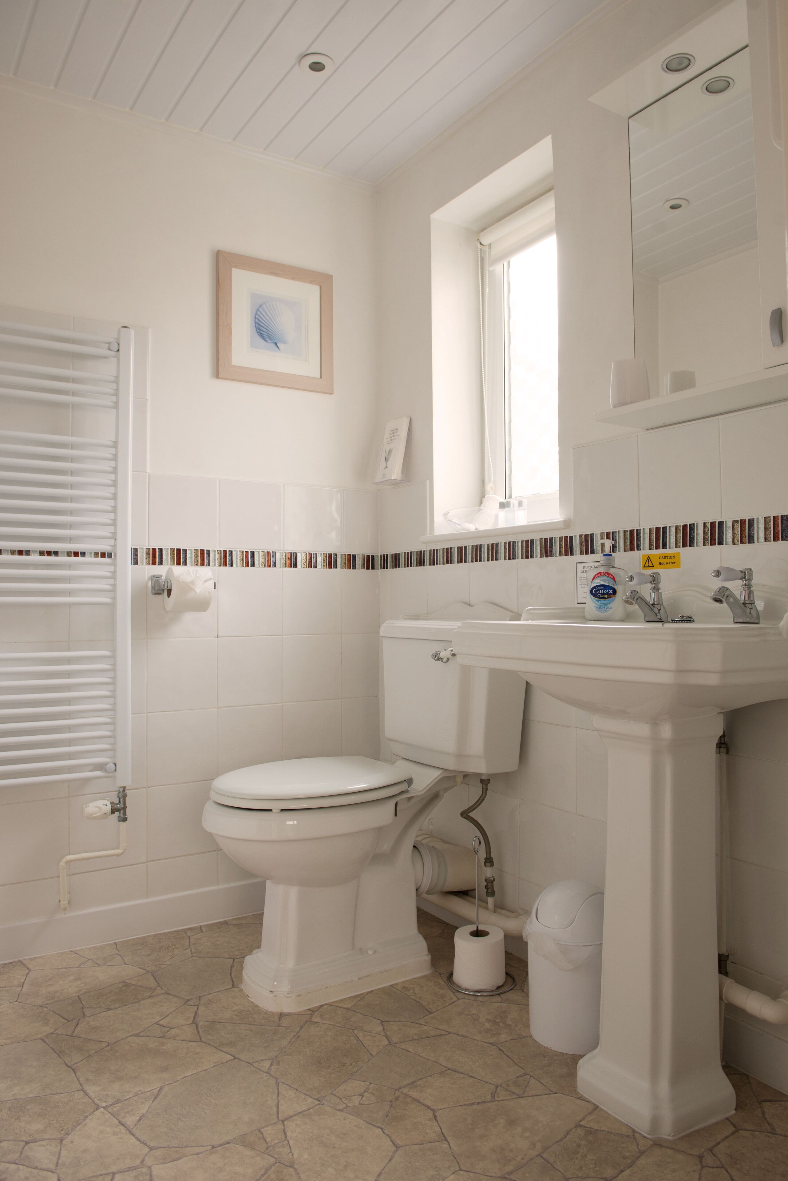 A bathroom with a toilet, sink, and a window.