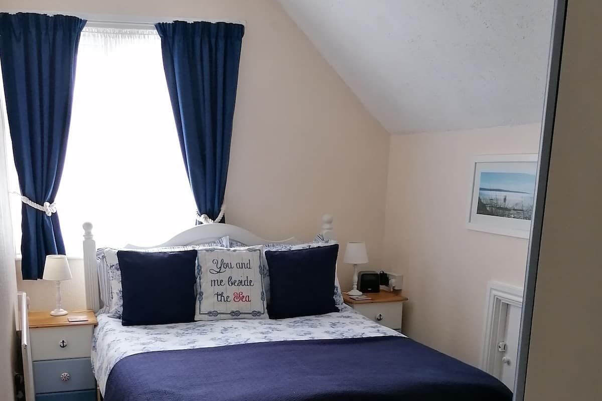 A bedroom with a bed, a nightstand, a lamp, and a framed picture on the wall.