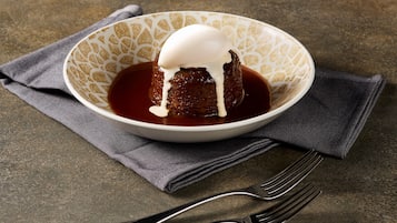 A dessert in a bowl with a napkin and fork beside it.