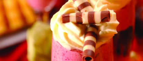 A dessert with a pink and yellow swirl, topped with chocolate sticks.