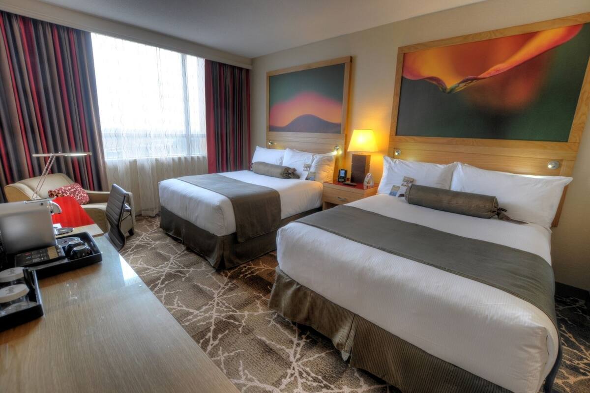 Hotelkamer met twee bedden, een bureau met computer, een stoel en een raam met gordijnen.