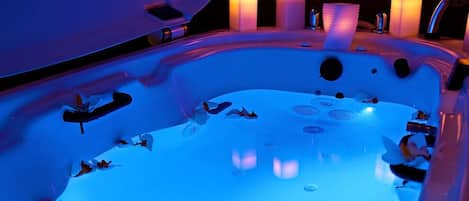 A hot tub with multiple jets, surrounded by candles and a modern design.
