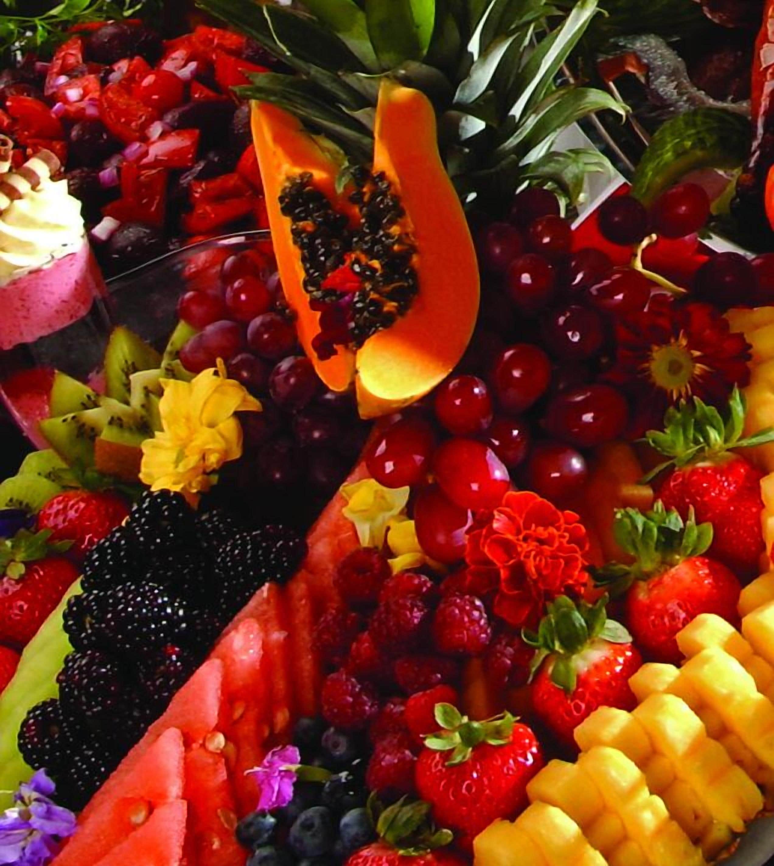 Una bandeja de frutas con diversas frutas y una porción de papaya.