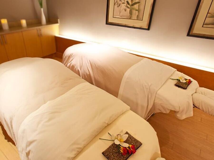 Een hotelkamer met twee bedden, een houten vloer en een muur met ingelijste kunstwerken.