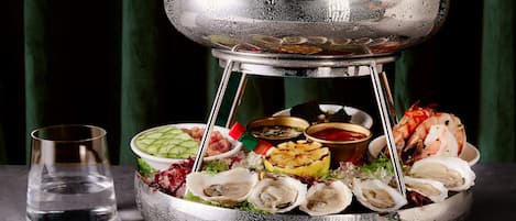 A seafood platter with various types of seafood and sides, including oysters and shrimp, on a metal stand.