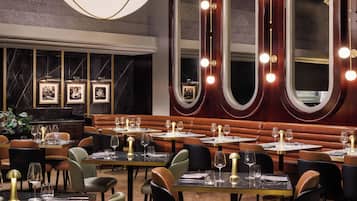 A restaurant interior with round tables, cushioned booths, and a large chandelier.