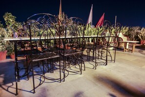 A patio with a metal table and chairs, surrounded by potted plants. - Hotel Kalyan (Jaipur)