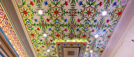 A ceiling with intricate floral patterns and recessed lighting.