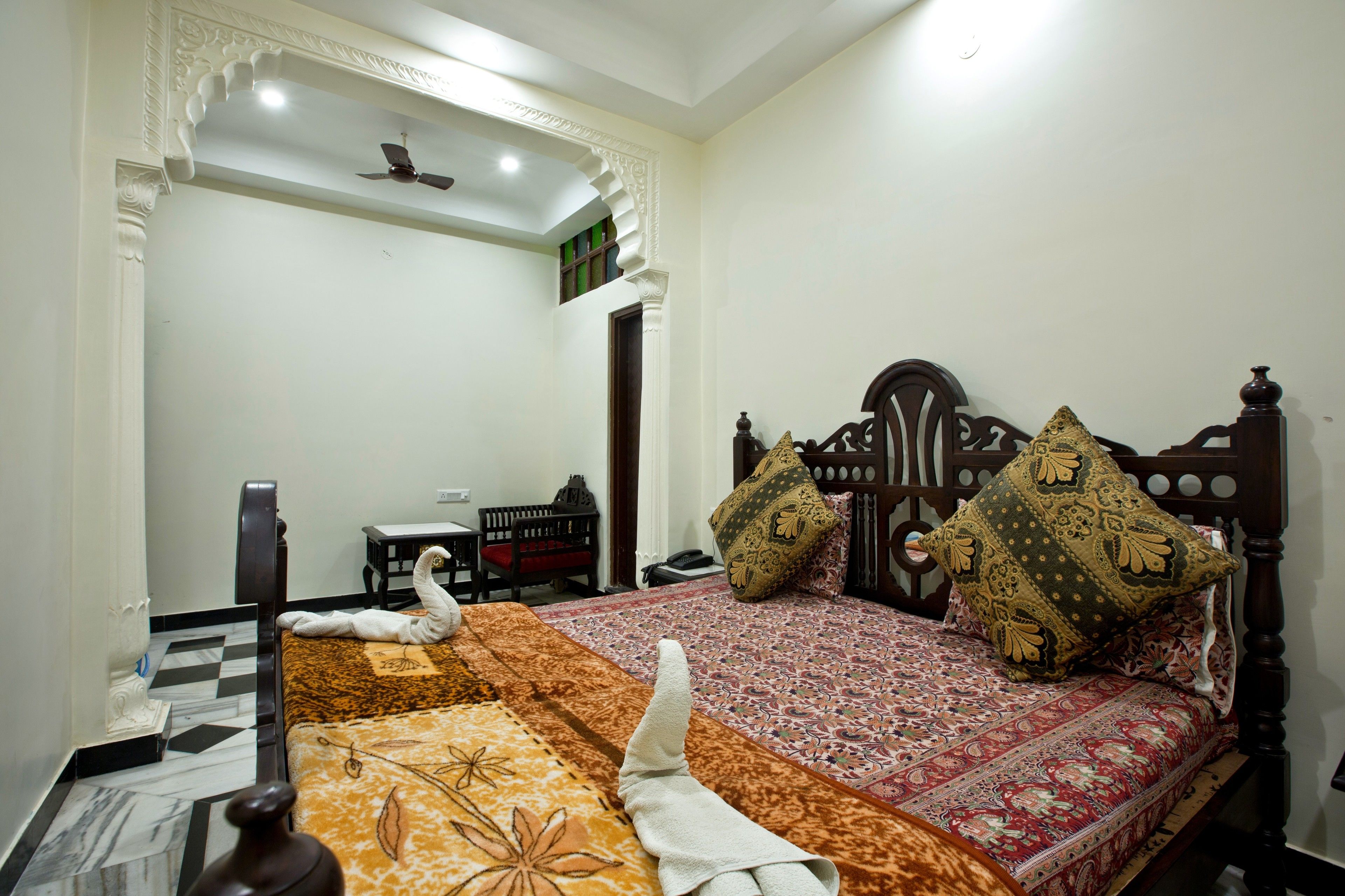 A neatly arranged bedroom with a bed, pillows, a bedside table, and a chair.