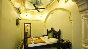 Een hotelkamer met een bed, nachtkastje en een plafondventilator.
