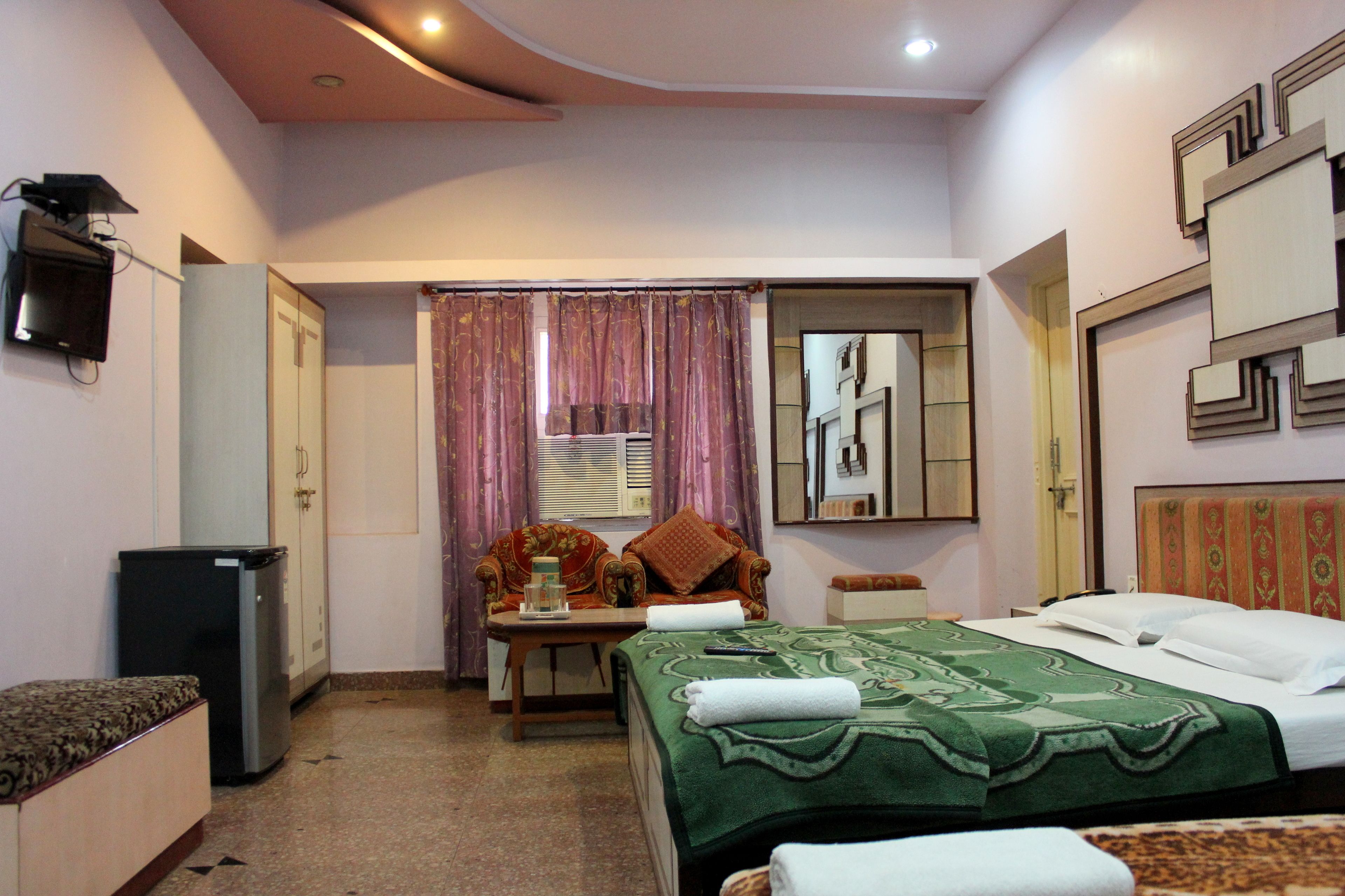A hotel room with a bed, a desk, a chair, a television, and a wardrobe.