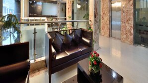 A modern lobby with a leather sofa, a coffee table, and a chandelier. - Hotel Marble Arch (New Delhi)