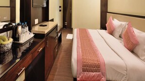 A hotel room with a bed, a desk with a mirror, a television, and a minibar. - Hotel Marble Arch (New Delhi)