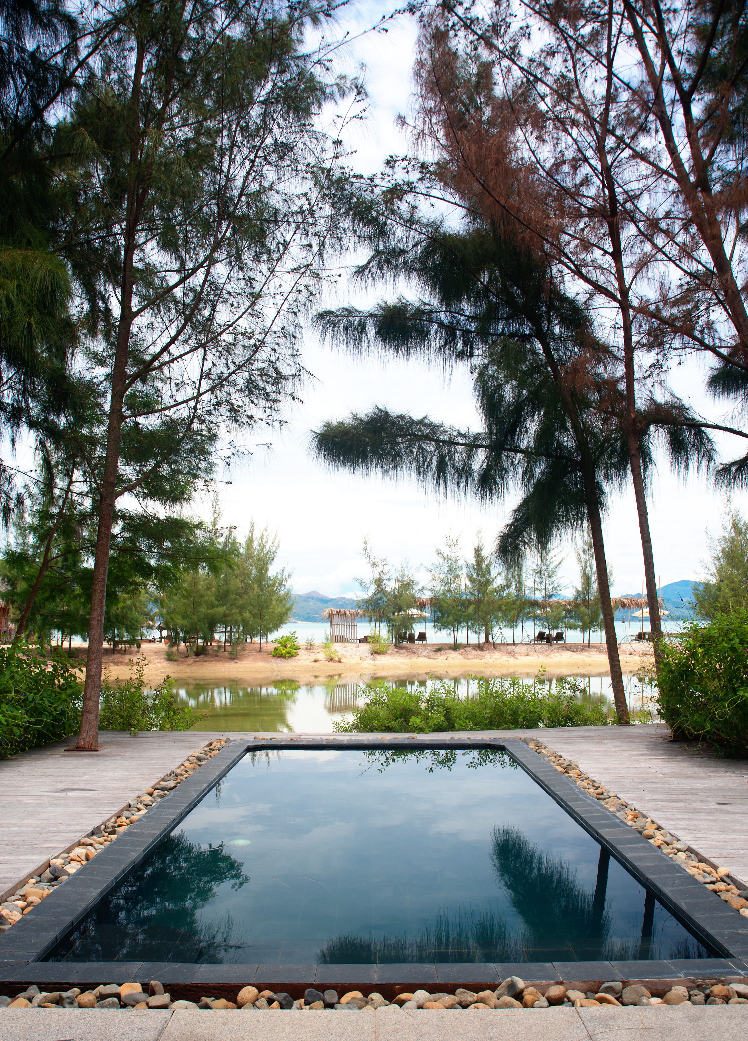 A serene outdoor pool area with a clear view of a lake and distant mountains.