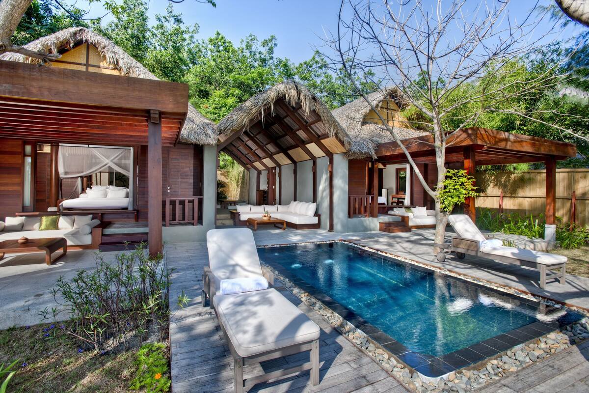 A pool area with lounge chairs, a hot tub, and wooden cabins.