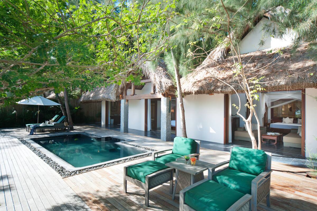 A pool area with lounge chairs and a thatched-roof structure.