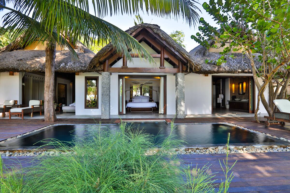 A resort with a pool, thatched-roof structures, and a well-maintained garden.