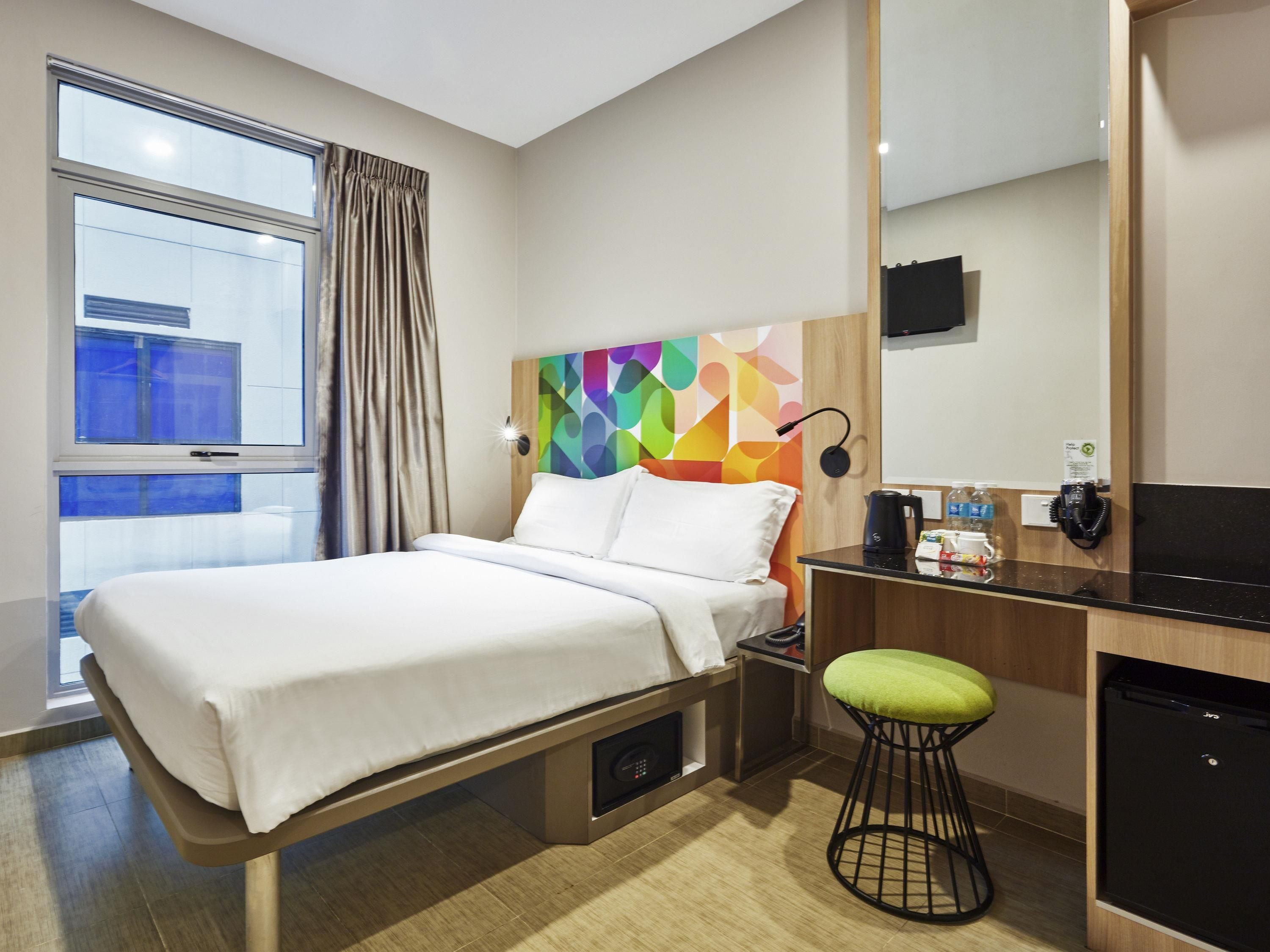Ein Hotelzimmer mit einem Bett, einem Schreibtisch, einem Sessel, einer Kaffeemaschine und einem Fernseher.