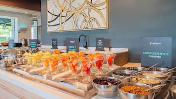 A buffet with various fruits, yogurt, and toppings.