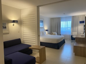 Relax in a spacious room with a large bed, sofa, and desk, featuring a wall-mounted TV and a framed picture.