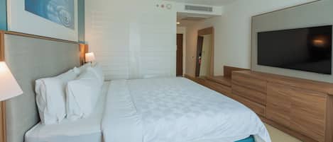 A hotel room with a bed, a TV, a desk, and a painting on the wall.