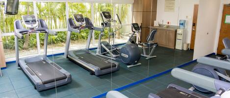A gym with treadmills, ellipticals, and a water dispenser.