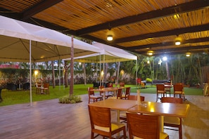 Enjoy al fresco dining under a spacious canopy, surrounded by lush greenery and palm trees.