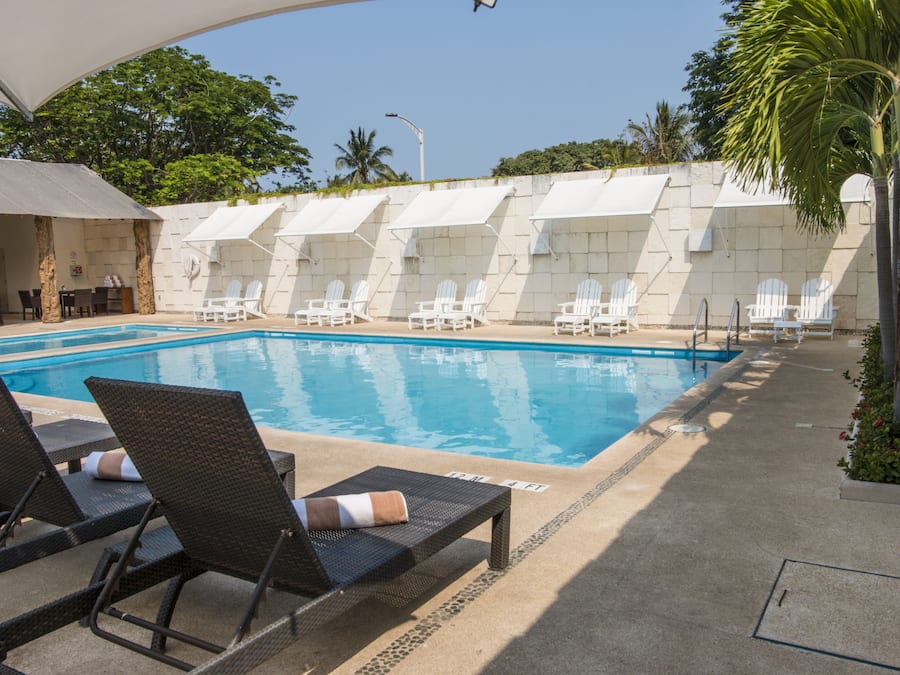 Una piscina al aire libre, sillones reclinables de piscina