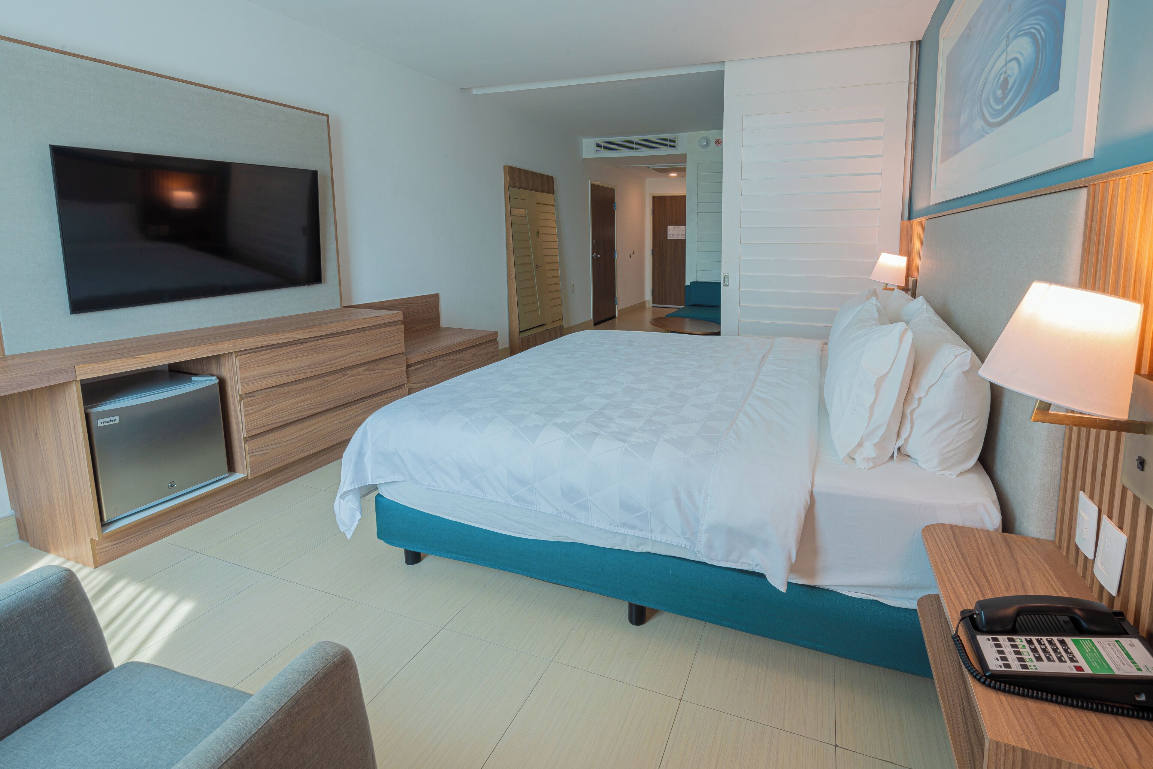A hotel room with a bed, a TV, a desk with a phone, and a seating area.
