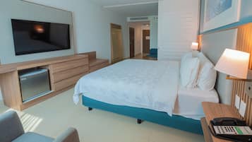 A hotel room with a bed, a TV, a desk with a phone, and a seating area.