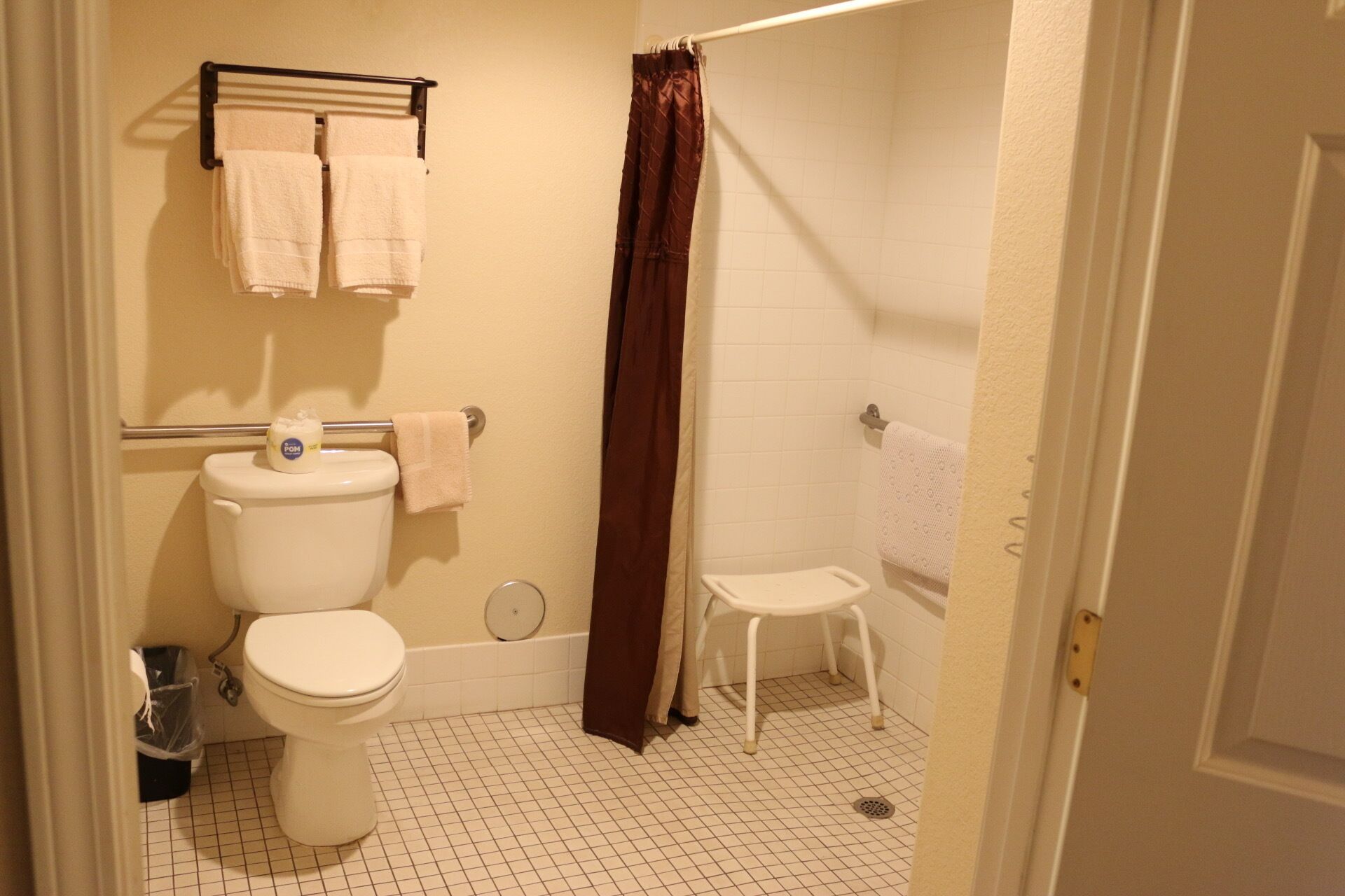 A small bathroom with a toilet, a shower, and a bathtub. There is a towel rack with two towels above the toilet.