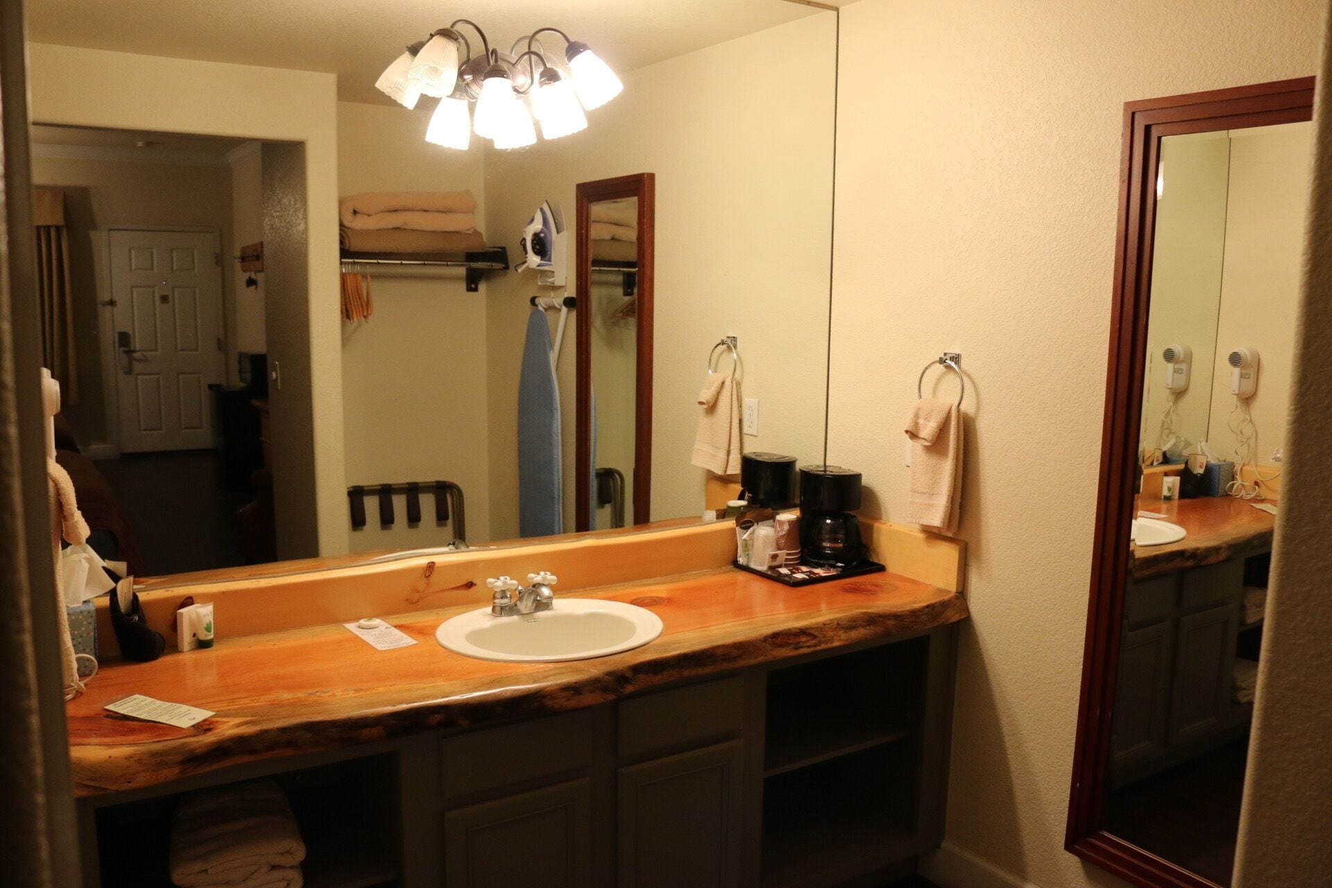 A bathroom with a wooden vanity, two sinks, a mirror, and a ceiling light fixture.