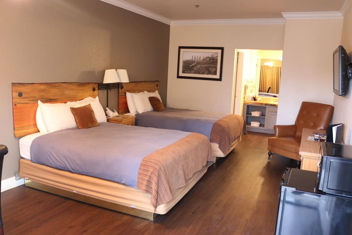 Une chambre d’hôtel avec deux lits, un bureau, une chaise et un téléviseur.